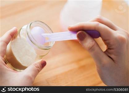 food and nutrition concept - mother hands with jar of infant formula and scoop preparing baby milk. hands with jar and scoop making formula milk