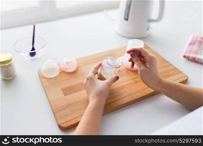 food and nutrition concept - mother hands with jar, scoop and baby bottle preparing infant formula milk. hands with infant formula making baby milk