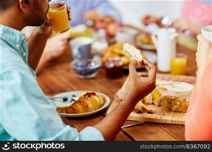 food and people concept - close up of man drinking orange juice and eating toast with cream cheese. close up of man drinking orange juice with toast