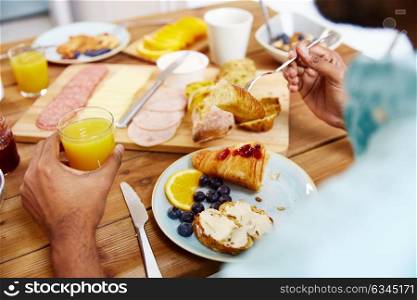 food and people concept - close up of man eating croissant with orange juice for breakfast. close up of man eating croissant with orange juice