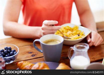 food and people concept - close up of woman eating cereals with coffee for breakfast at home. close up of woman eating cereals with coffee
