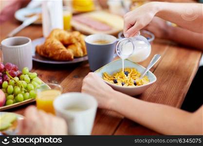food and people concept - hands of woman eating cereals for breakfast and adding milk. hands of woman eating cereals for breakfast