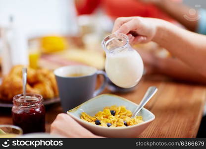 food and people concept - hands of woman eating cereals for breakfast and pouring milk. hands of woman eating cereals for breakfast