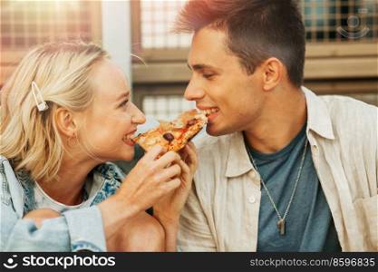 food and people concept - happy young couple eating takeaway pizza outdoors. happy couple eating pizza outdoors