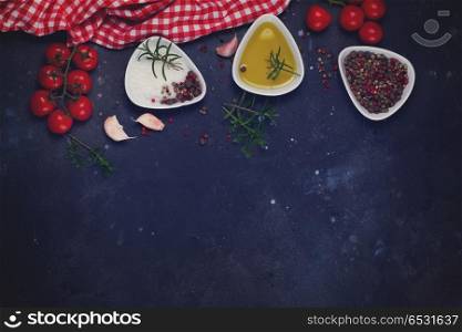 Food background - spices, olive oil and tomatoes on black background, retro toned. Food background with spices. Food background with spices
