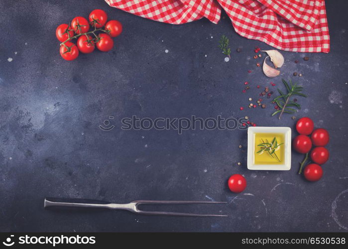 Food background - spices, olive oil, meat fork and tomatoes on black background, retro toned. Food background with spices. Food background with spices