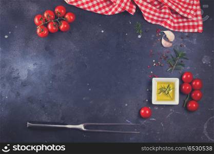 Food background - spices, olive oil, meat fork and tomatoes on black background, retro toned. Food background with spices. Food background with spices