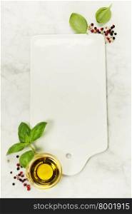 Food background with Empty vintage cutting board, olive oil, basil and pepper on white marble background