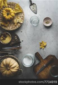 Food background with pumpkins, millet in bowl, cardamon spice and kitchen utensils on grey concrete kitchen table. Vegan cooking preparation at home with healthy nutritious ingredients. Top view.