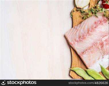 Food background with Raw fish fillet and fresh seasoning on white wooden background, top view, border