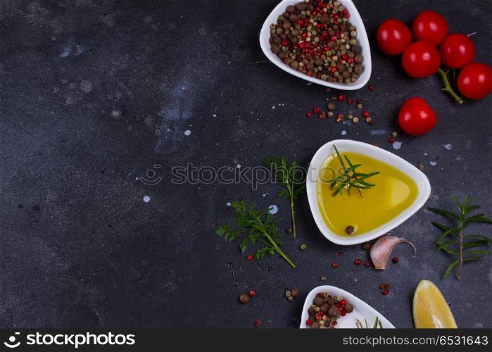 Food background with spices. Food background - olive oil and spices on black stone background, flat lay scene