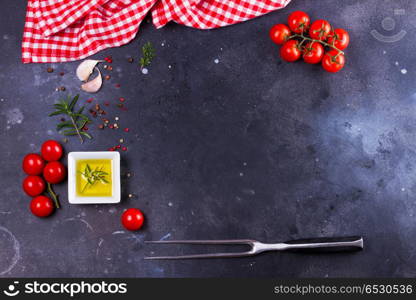 Food background with spices. Food background - spices, olive oil, meat fork and tomatoes on black background