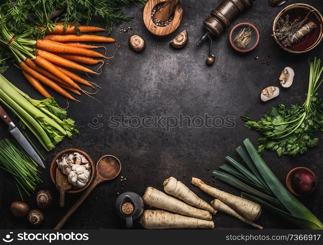 Food background with various organic farm vegetables on dark rustic table with kitchen utensils, herbs and spices, top view. Frame. Copy space. Vegan and vegetarian food concept. Healthy lifestyle