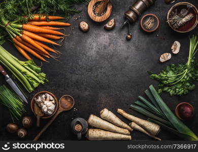 Food background with various organic farm vegetables on dark rustic table with kitchen utensils, herbs and spices, top view. Frame. Copy space. Vegan and vegetarian food concept. Healthy lifestyle