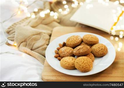 food, bakery and hygge concept - oatmeal cookies on wooden board at home. oatmeal cookies with almonds on plate at home