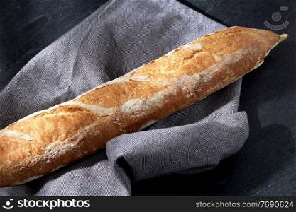food, baking and cooking concept - close up of baguette bread on kitchen towel. close up of baguette bread on kitchen towel