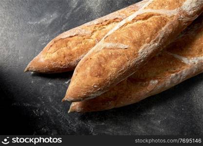 food, baking and cooking concept - close up of baguette bread on table over dark background. close up of baguette bread on table