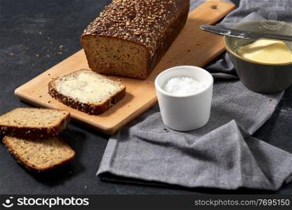 food, baking and cooking concept - close up of bread, butter in bowl, table knife and salt in cup on towel. close up of bread, butter, knife and salt on towel