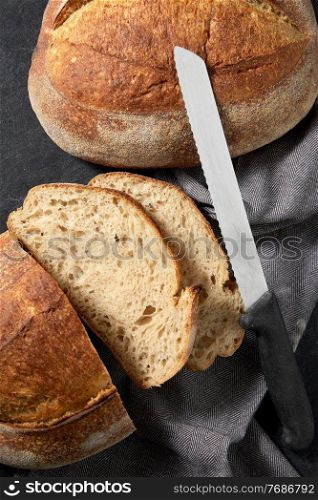 food, baking and cooking concept - close up of homemade craft bread with kitchen knife. homemade craft bread with kitchen knife