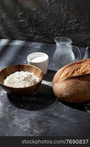food, baking and cooking concept - homemade craft bread, wheat flour, salt and water in glass jug on table. bread, wheat flour, salt and water in glass jug