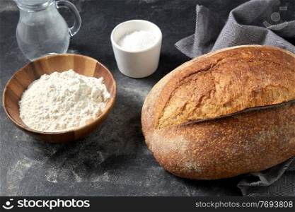 food, baking and cooking concept - homemade craft bread, wheat flour, salt and water in glass jug on table. bread, wheat flour, salt and water in glass jug