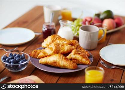 food, baking and eating concept - plate of croissants on wooden table at breakfast. plate of croissants on wooden table at breakfast