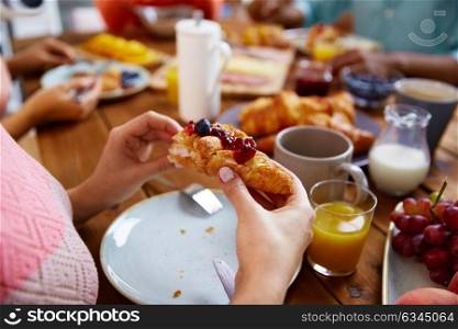 food, baking and people concept - hands of woman eating croissant for breakfast at table. hands of woman eating croissant for breakfast