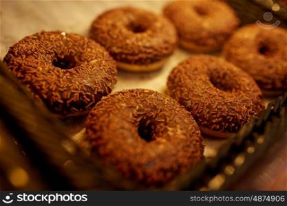 food, baking and sale concept - close up of chocolate donuts at bakery or grocery store