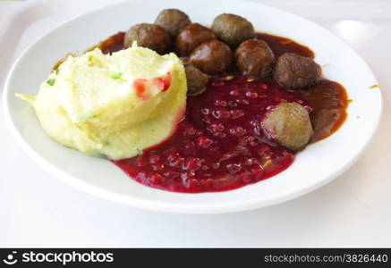 Food being eaten. Swedish meatballs potatoes cranberry on dish. A traditional scandinavian culinary.