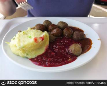 Food being eaten. Swedish meatballs potatoes cranberry on dish. A traditional scandinavian culinary.