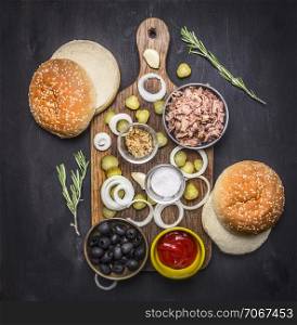 Food burger with tuna Food burger with tuna, herbs, cucumbers, olives, onions and sauce on a cutting board on wooden rustic background top view