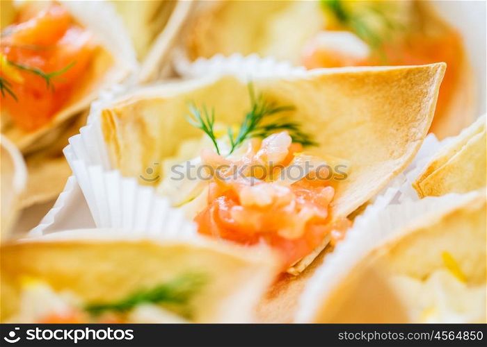 food, catering and unhealthy eating concept - close up of dough cornet with salmon fish filling