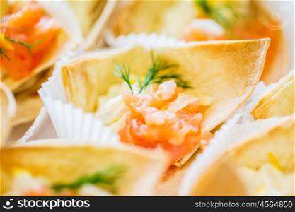 food, catering and unhealthy eating concept - close up of dough cornet with salmon fish filling