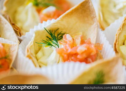 food, catering and unhealthy eating concept - close up of dough cornet with salmon fish filling