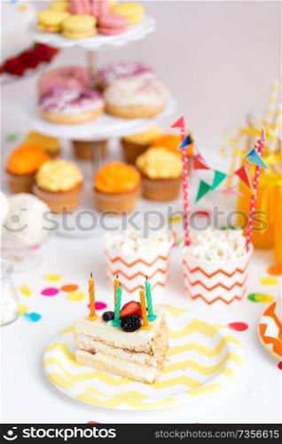 food, celebration and festive concept - piece of cake with candles on plate at birthday party. piece of cake on plate at birthday party