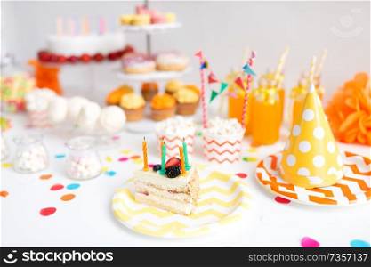 food, celebration and festive concept - piece of cake with candles on plate at birthday party. piece of cake on plate at birthday party