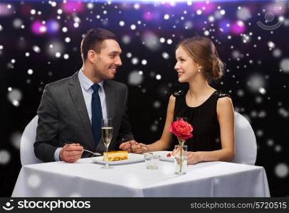 food, christmas, holidays and people concept - smiling couple eating dessert at restaurant over night lights background