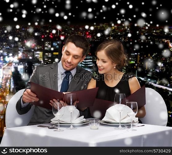 food, christmas, holidays and people concept - smiling couple with menus at restaurant over snowy night city background