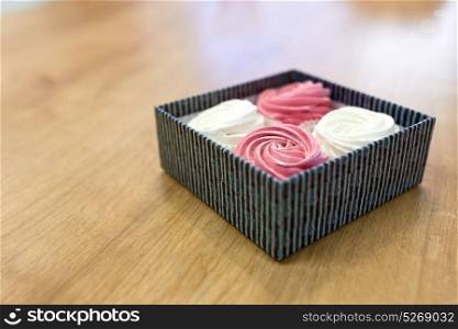 food, confection and sweets concept - zephyr, marshmallow or whipped cream in gift box on wooden table. zephyr or marshmallow dessert in gift box