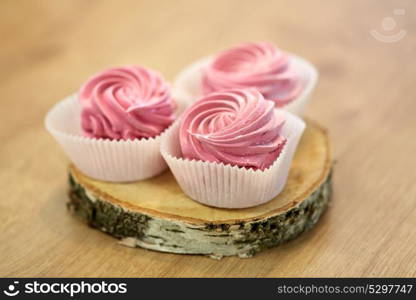 food, confection and sweets concept - zephyr, marshmallow or whipped cream on wooden stand. zephyr or marshmallow on wooden stand