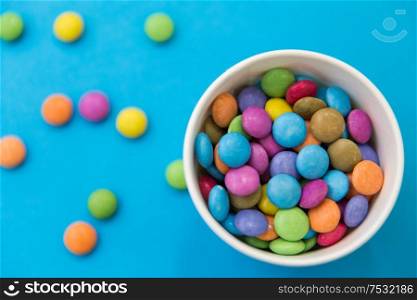 food, confectionery and sweets concept - candy drops in paper cup on blue background. candy drops in paper cup on blue background