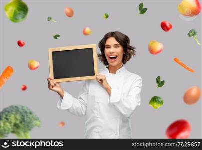 food cooking, advertisement and people concept - happy smiling female chef holding black chalkboard over fruits and vegetables on grey background. happy female chef holding chalkboard over food
