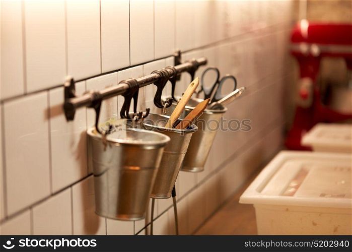 food, cooking and baking concept - bakery kitchen tools hanging on wall in buckets. bakery kitchen tools hanging on wall in buckets