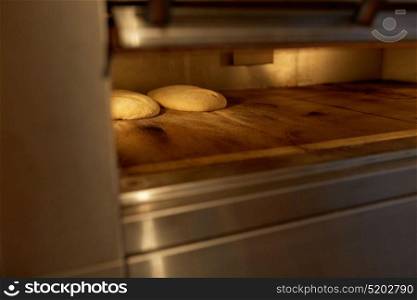 food, cooking and baking concept - yeast bread dough in oven at bakery kitchen. yeast bread dough in oven at bakery kitchen