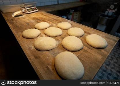 food, cooking and baking concept - yeast bread dough rising on bakery kitchen table. yeast bread dough on bakery kitchen table