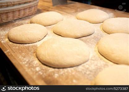 food, cooking and baking concept - yeast bread dough rising on wooden kitchen table at bakery. yeast bread dough on bakery kitchen table