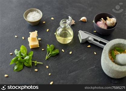 food cooking and culinary concept - parmesan cheese, pine nuts, vinegar and garlic for basil pesto sauce making on stone table. ingredients for basil pesto sauce on stone table