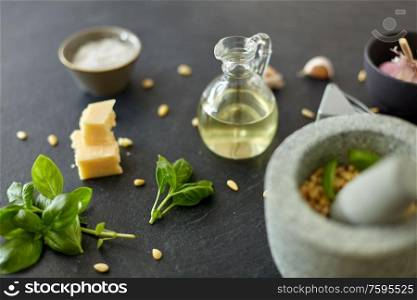 food cooking and culinary concept - parmesan cheese, pine nuts, vinegar and garlic for basil pesto sauce making on stone table. ingredients for basil pesto sauce on stone table