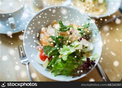 food, cooking and eating concept - close up of caesar salad on plate at restaurant or home