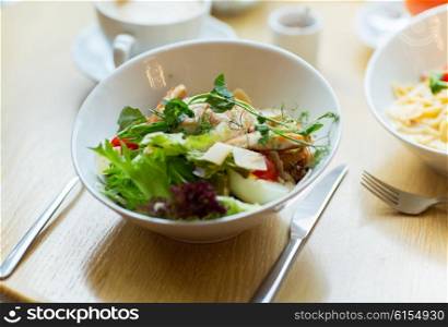 food, cooking and eating concept - close up of caesar salad on plate at restaurant or home
